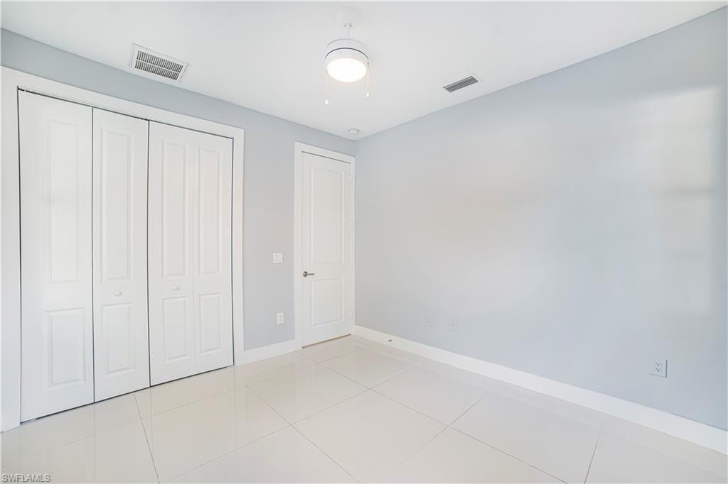 Unfurnished bedroom featuring a closet, light tile patterned floors, and ceiling fan