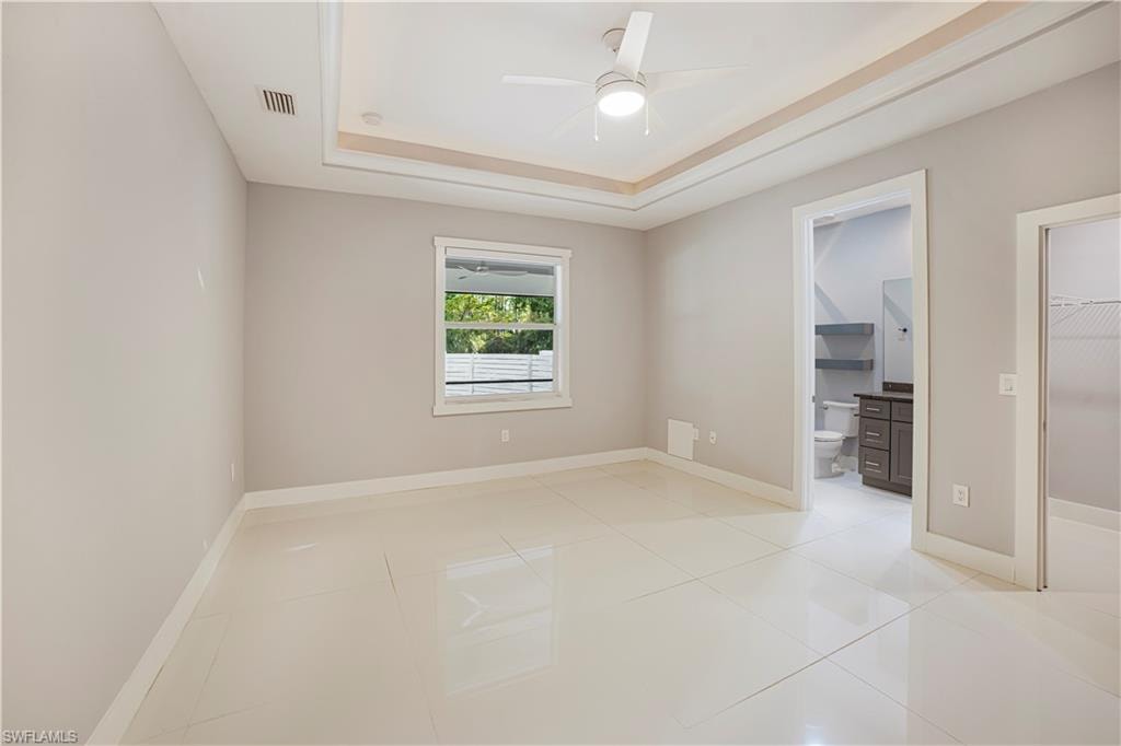 Tiled spare room with a tray ceiling and ceiling fan
