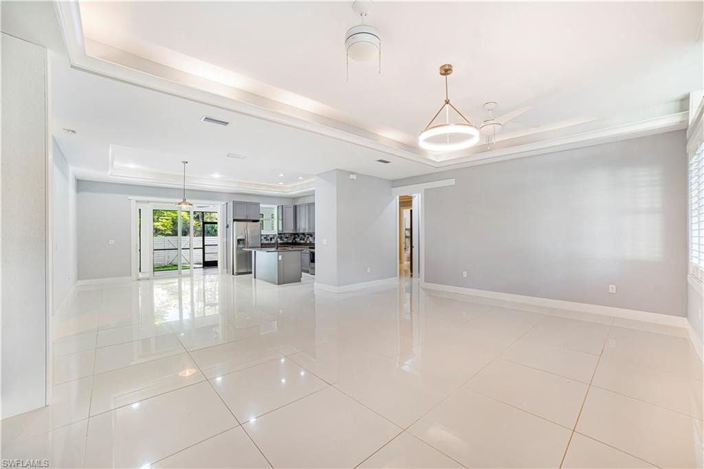 Unfurnished living room featuring light tile patterned floors and a raised ceiling