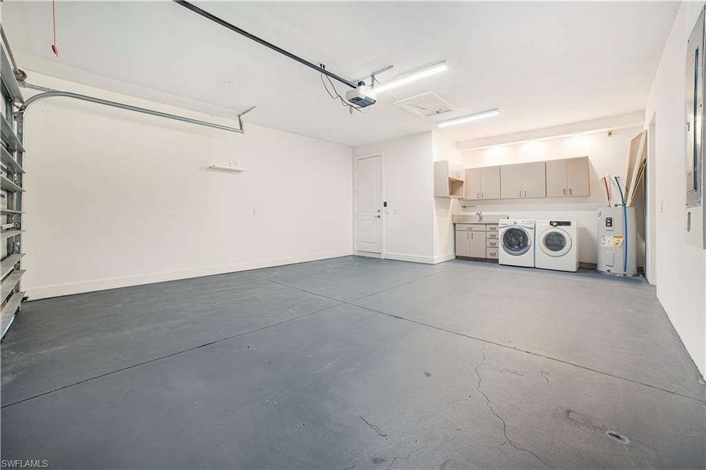 Garage featuring a garage door opener, electric water heater, and independent washer and dryer