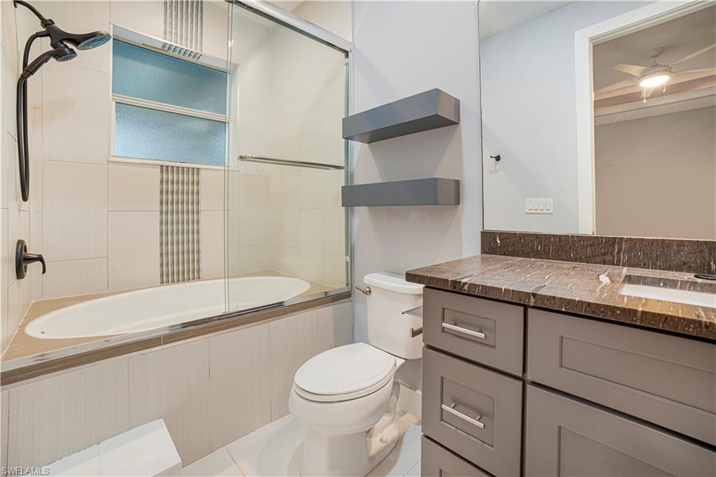 Full bathroom with vanity, toilet, tile patterned flooring, and bath / shower combo with glass door