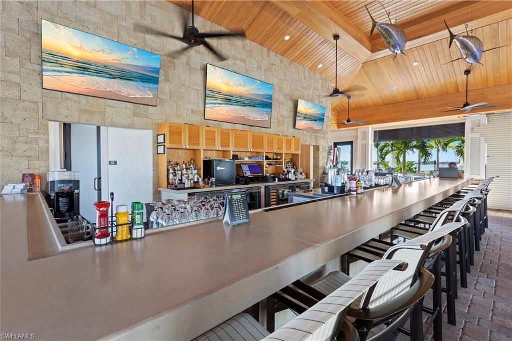 Expansive bar area featuring a long counter, stone-finish accent walls, and a vaulted wood-plank ceiling