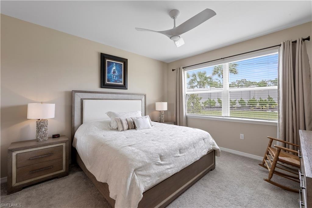 The Primary bedroom featuring a large window, neutral carpeting, and a ceiling fan