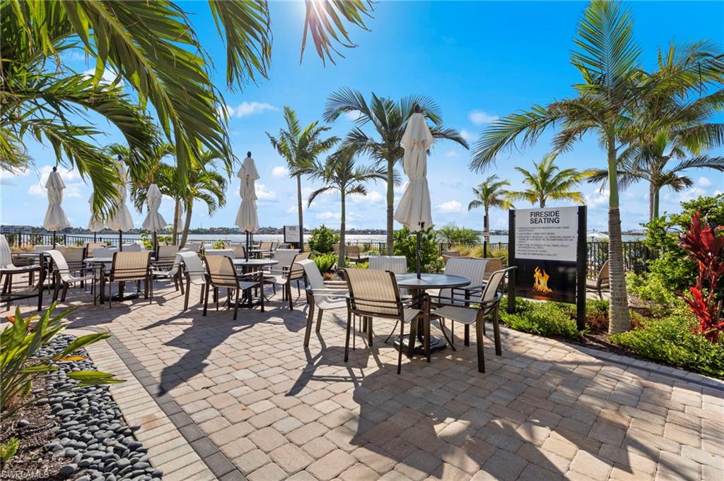Expansive paver patio with multiple seating areas, mature palm trees, and a distant water feature