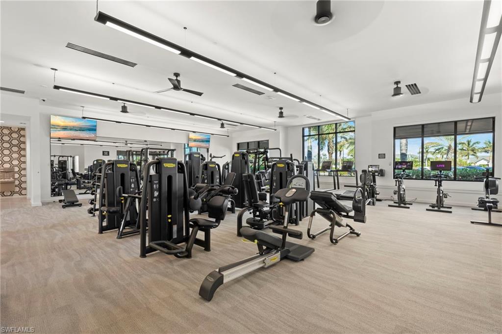 Spacious fitness center featuring a comprehensive array of exercise equipment, large windows, ceiling fans, and recessed lighting