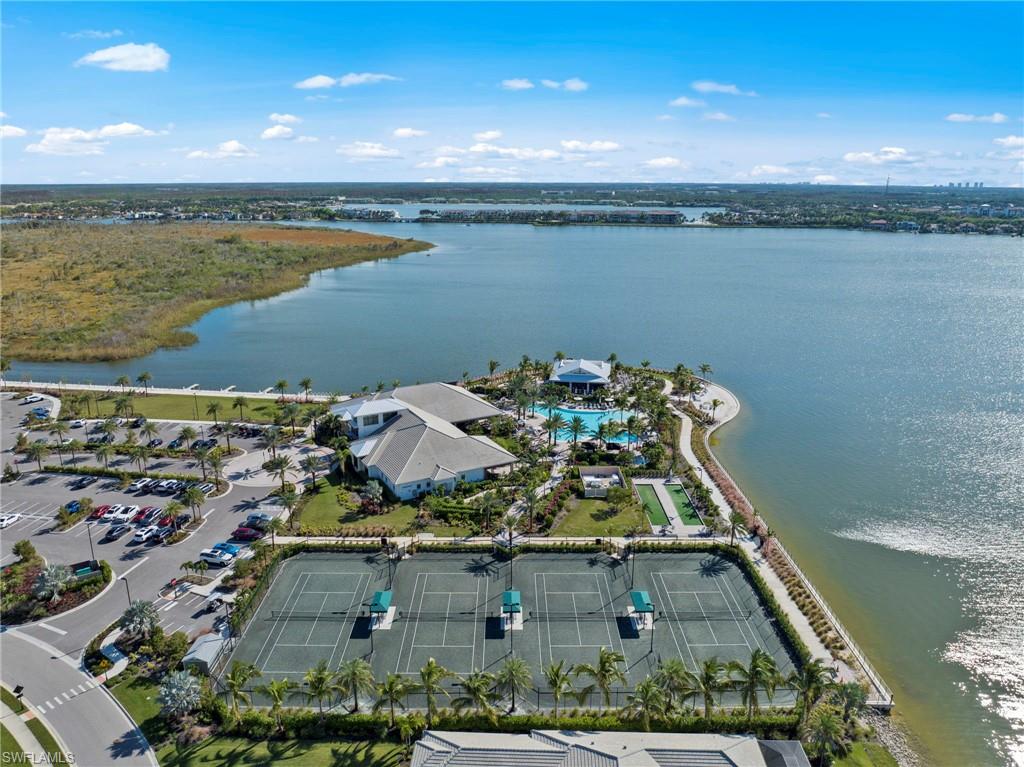 Waterfront recreational facility featuring multiple tennis courts, a resort-style swimming pool, and a structured parking area