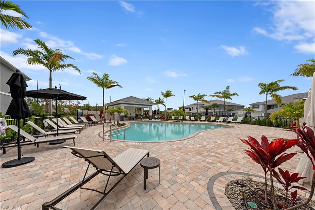 LOCAL COMMUNITY POOL. This property is the closest to the Resort-style pool area featuring a freeform swimming pool, extensive paver deck, surrounding palm trees, and a shaded cabanas