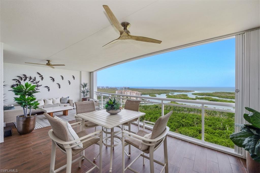 Expansive outdoor living area featuring wood-finish flooring, a white railing system, and dual ceiling fans