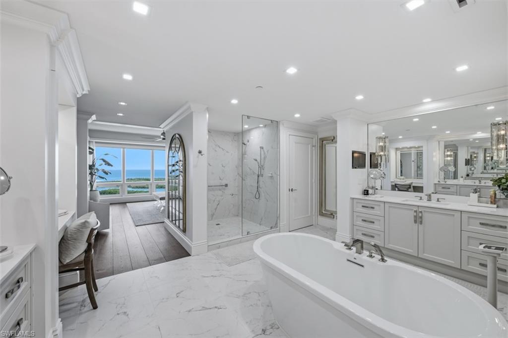 Freestanding soaking tub with a floor-to-ceiling window offering water scenery