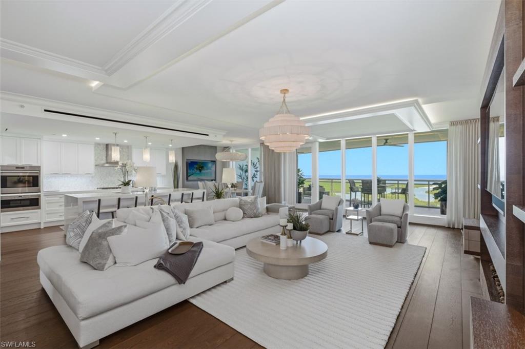 Spacious living area featuring wood-finish flooring, a contemporary chandelier, a built-in media console, and floor-to-ceiling windows