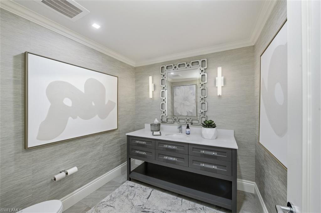Contemporary vanity with a white countertop and undermount sink, accented by two wall sconces and a decorative mirror