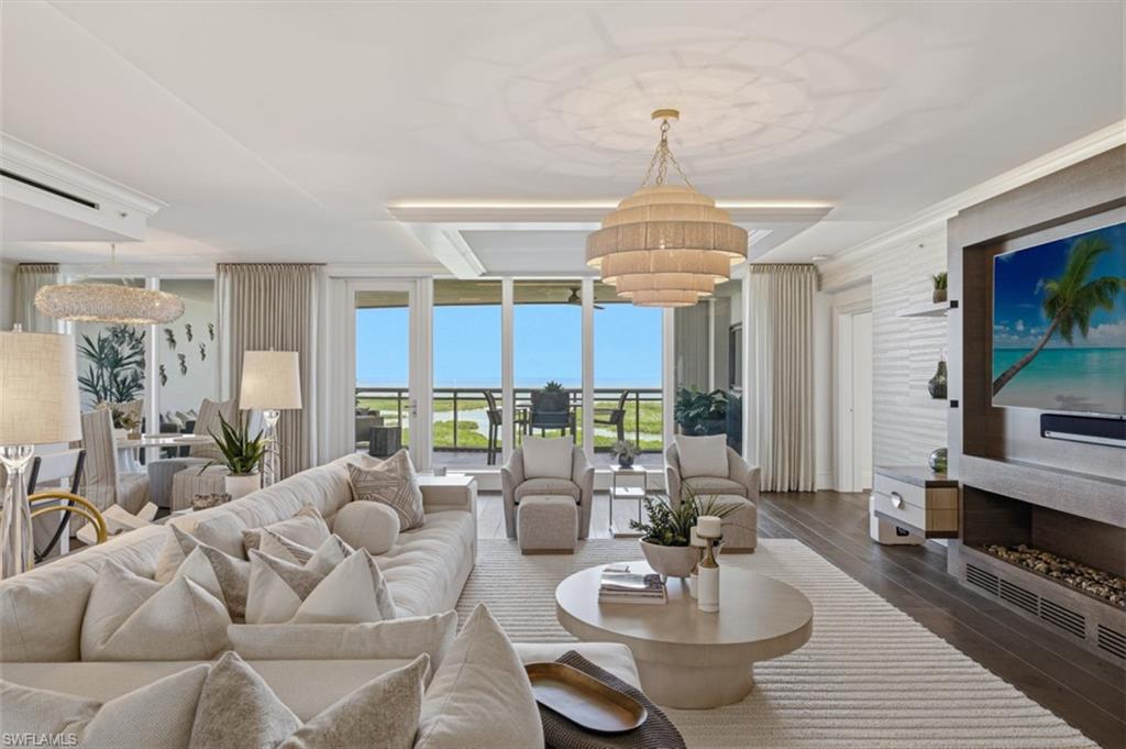 Expansive living area featuring wide plank wood-finish flooring, a contemporary stacked chandelier, and a built-in media center with a linear fireplace