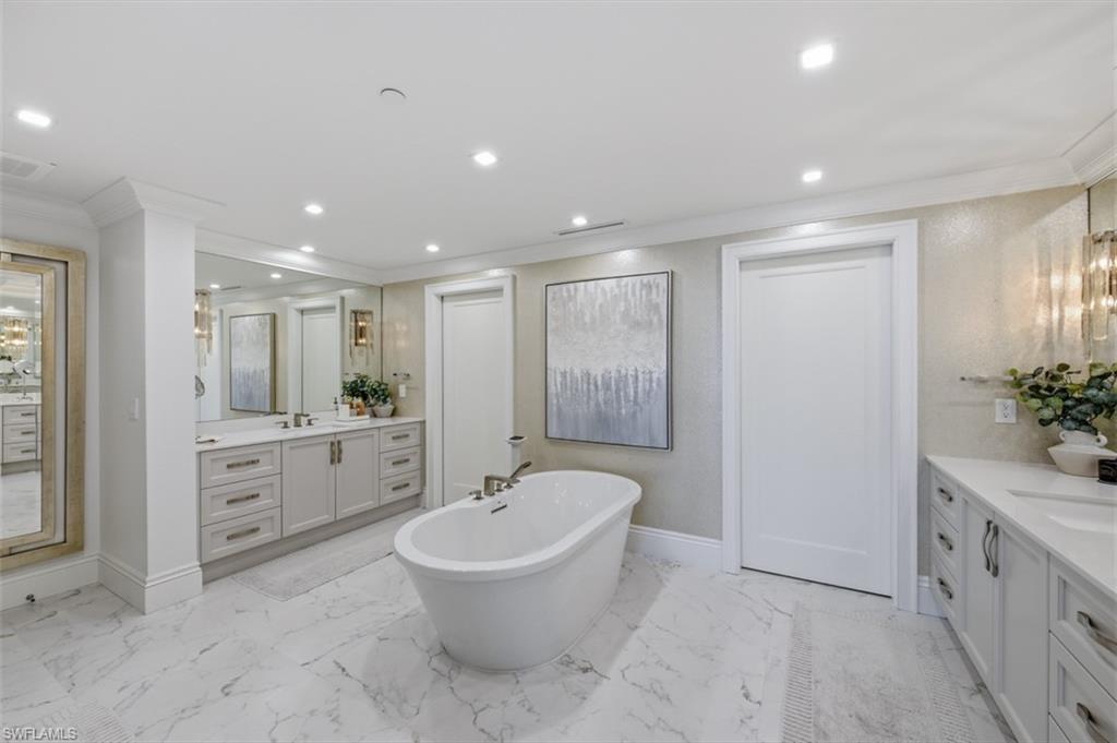 Freestanding soaking tub with a floor-mounted fixture, set against marble-look tile flooring