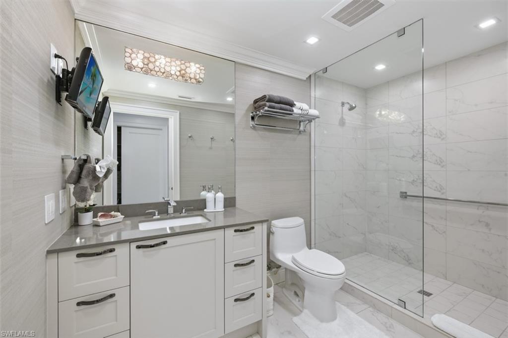 Bathroom featuring a glass-enclosed shower, white vanity with a grey countertop, integrated sink, and large wall mirror