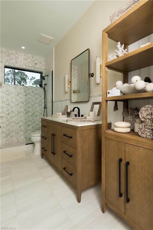 Bathroom featuring a wood-finish double vanity with a light-toned countertop, a rectangular mirror flanked by sconces, and a walk-in shower with patterned tile