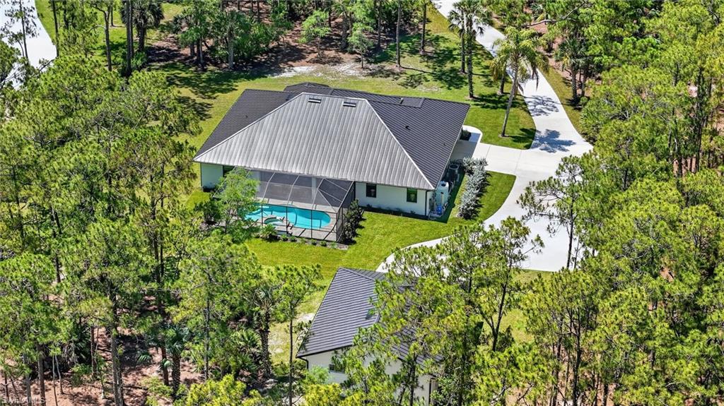 Expansive property featuring a main residence with a screened pool enclosure and a separate auxiliary structure