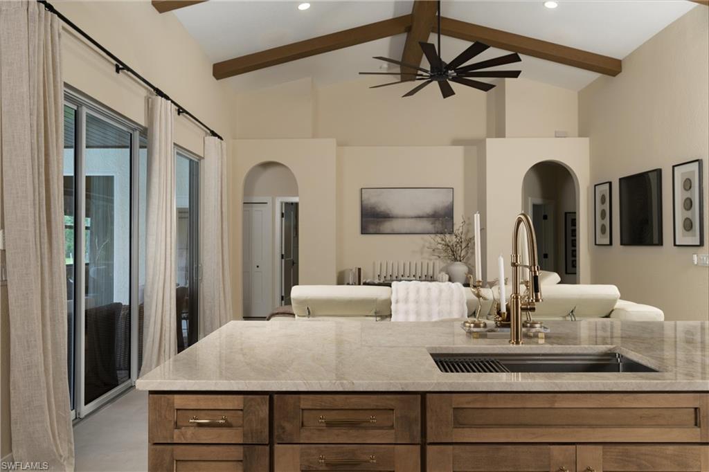 Gourmet kitchen island with an undermount sink and a brass-finish faucet, featuring wood-finish cabinetry and a stone countertop