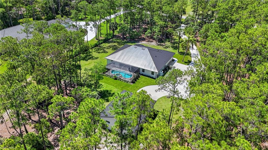 Aerial perspective showcasing a single-story residence with a dark shingle roof and a light-colored metal roof section