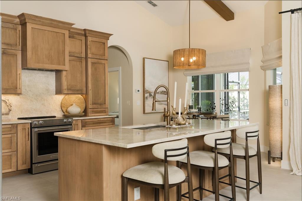 Gourmet kitchen with light wood-finish cabinetry, stainless steel range, and a spacious island featuring a light-toned countertop