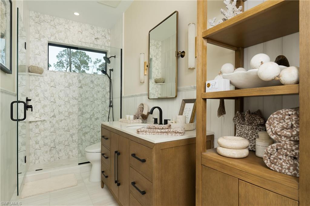 Contemporary bathroom featuring a walk-in shower with patterned tile, a wood-finish vanity with a white countertop, and a wall-mounted mirror