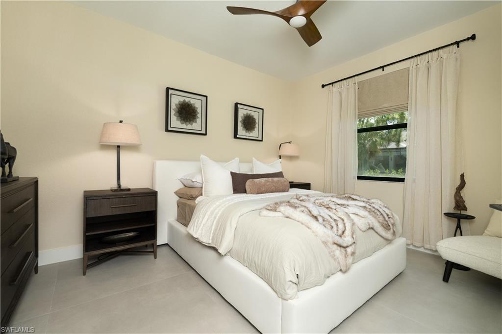 Spacious room featuring light-toned walls, a contemporary ceiling fan, and a large window with privacy shades and drapery