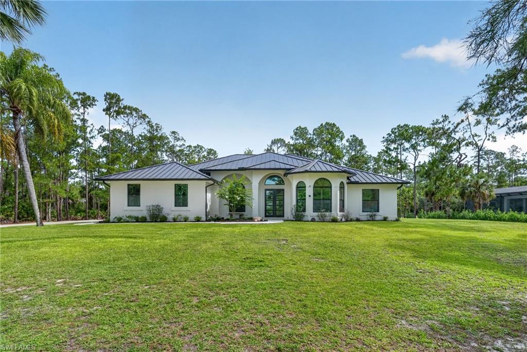 White stucco exterior with a dark metal roof and black-framed windows