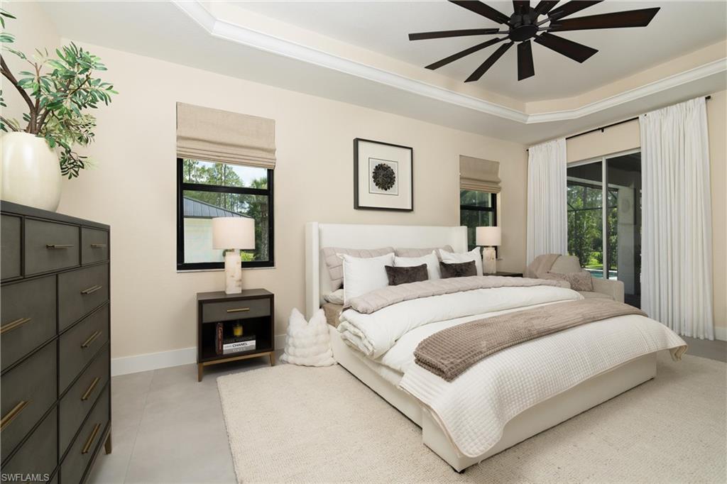 Bedroom featuring a multi-tiered tray ceiling with a dark-toned ceiling fan, light-toned wall paint, and tile flooring