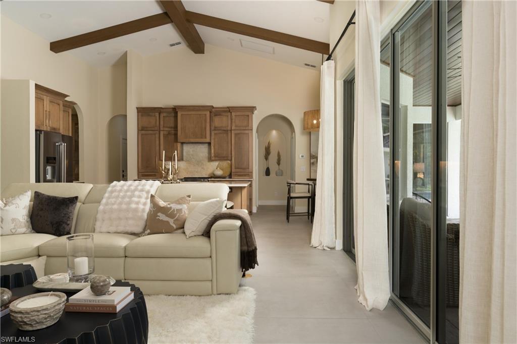 Spacious living area featuring exposed wood beams, vaulted ceilings, and light-toned walls