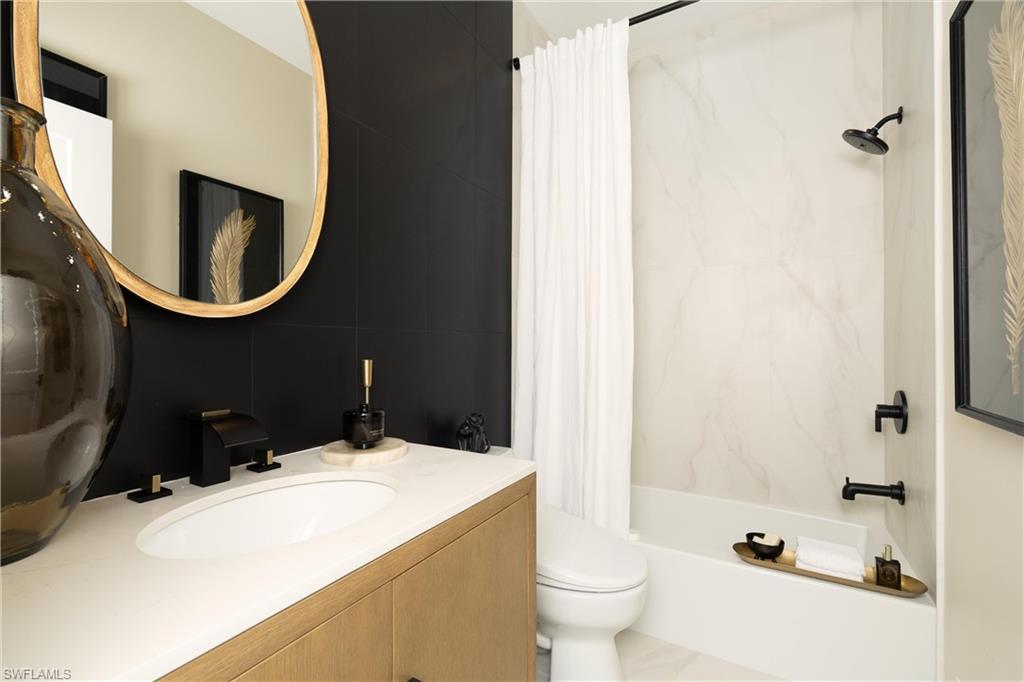 Contemporary bathroom featuring a wood-finish vanity with an integrated sink, matte black fixtures, and a gold-framed mirror