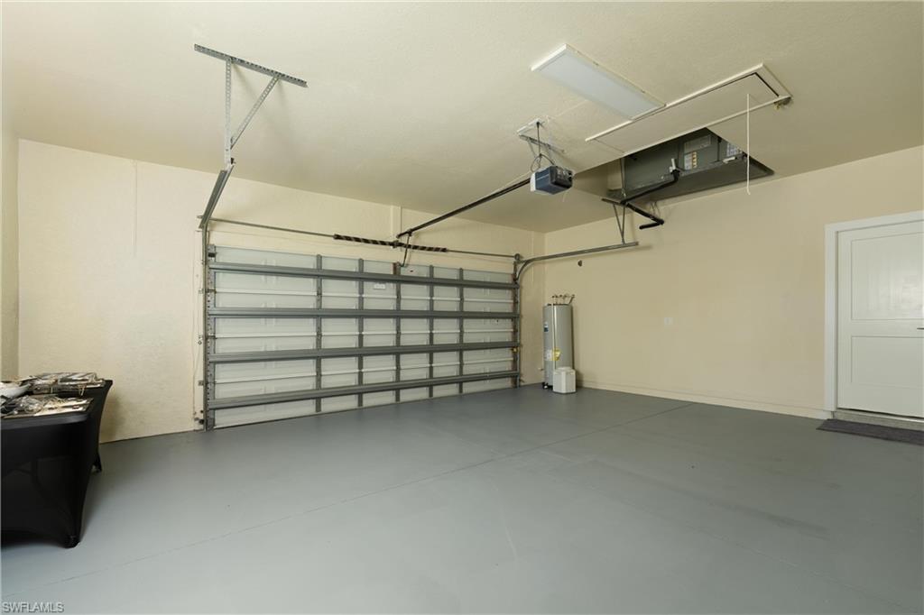 Spacious garage featuring a durable gray floor finish, automatic garage door opener, water heater, and an interior access door
