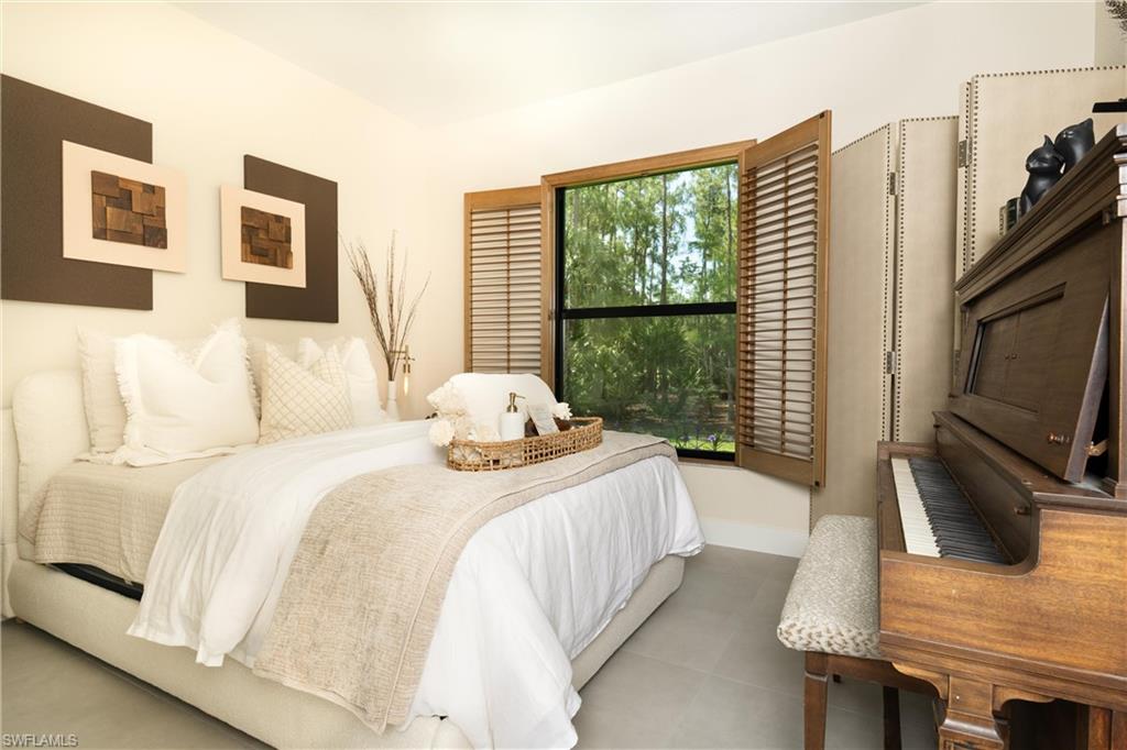 Bedroom featuring a large window with wooden plantation shutters, light-toned walls, and tile flooring