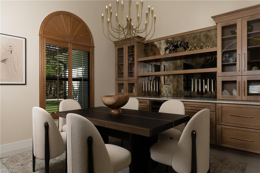 Dining area featuring a wood-finish arched window with louvered blinds, a multi-light chandelier, extensive built-in cabinetry with glass-front uppers, open shelving, and a built-in counter surface