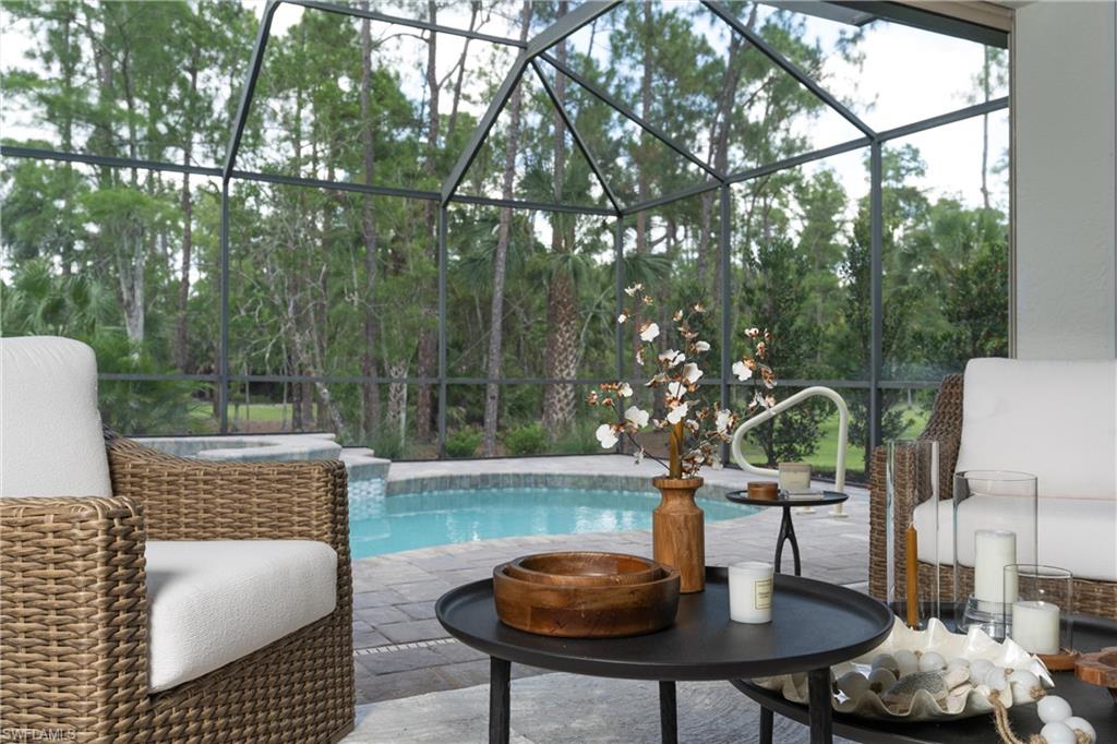 Screened outdoor living area featuring a swimming pool, integrated spa, and paver decking
