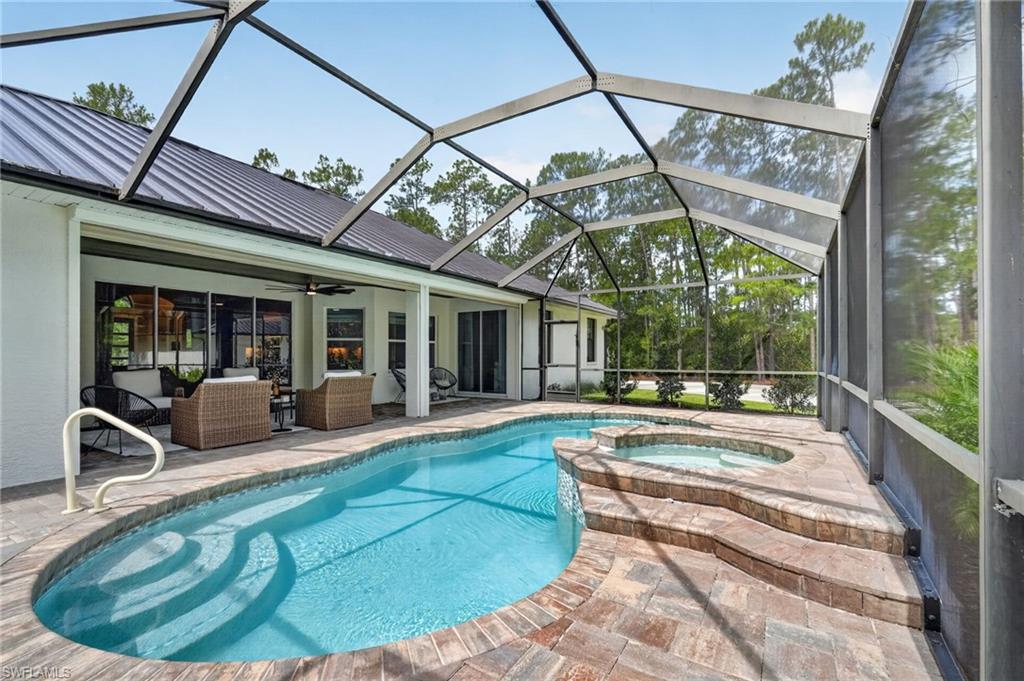 Screened enclosure featuring a custom-shaped swimming pool and an integrated spa