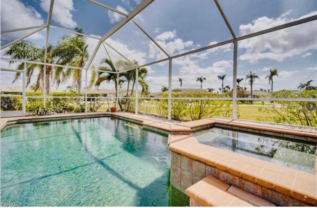 View of pool with glass enclosure, a sunroom, a pool with connected hot tub, and a patio