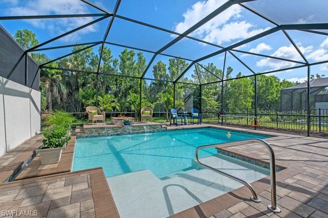 Screened outdoor pool area featuring a paver patio and integrated spa