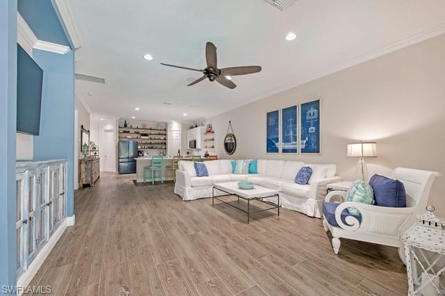Spacious living area featuring wood-finish flooring, crown molding, and recessed lighting