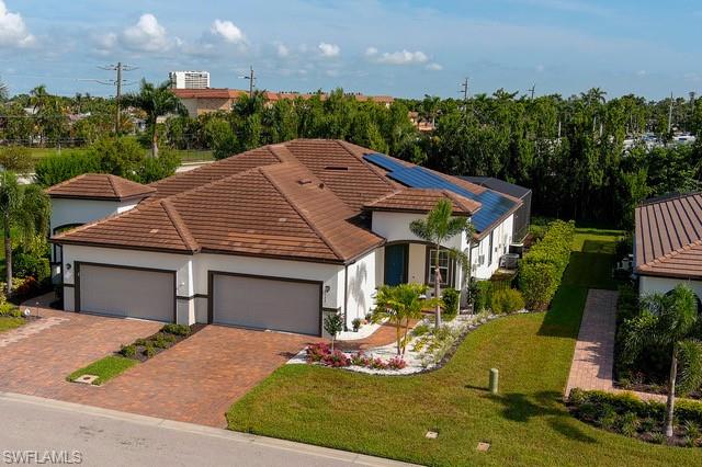 Contemporary home featuring a tile roof, solar panels, and a paver driveway