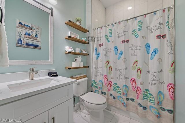 Bathroom featuring a white vanity with an integrated sink and light-colored countertop, framed mirror, wall-mounted floating wood shelves, and a tiled shower with a glass enclosure