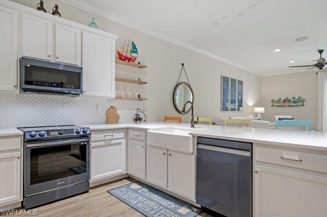 Modern kitchen featuring white cabinetry, quartz countertops, a farmhouse sink with a gooseneck faucet, a white scallop-tile backsplash, and wood-finish flooring