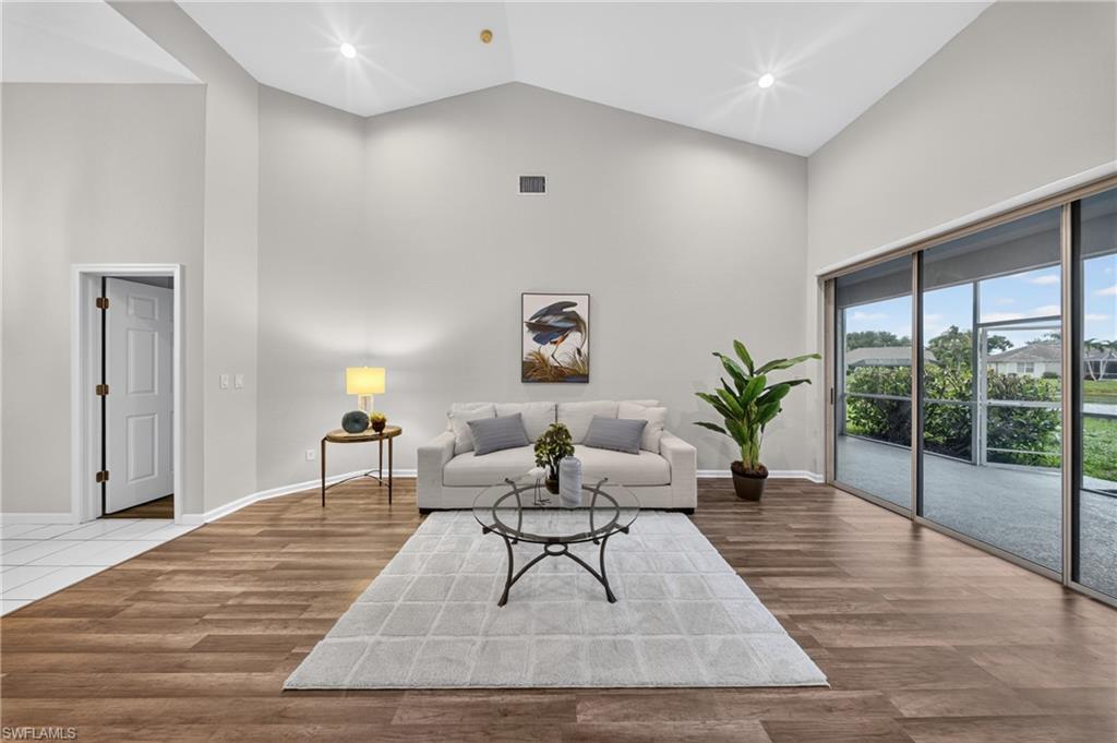Living area opens through sliders to the screened lanai and a tranquil pond view beyond.