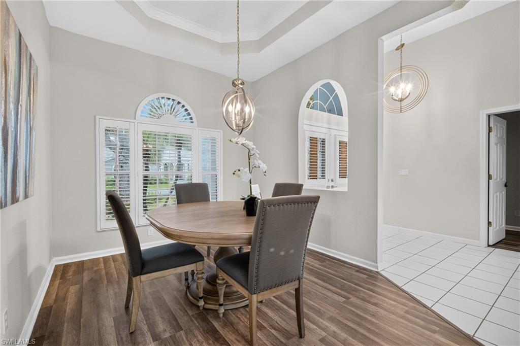 Elegant dining room under a tray ceiling with arched, plantation-shuttered windows.