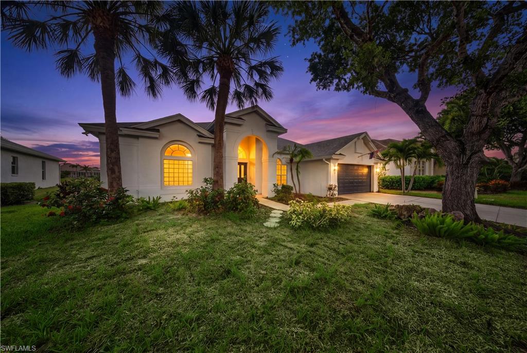 Virtual twilight image. Evening light highlights the home's signature arched architectural window and mature palms.