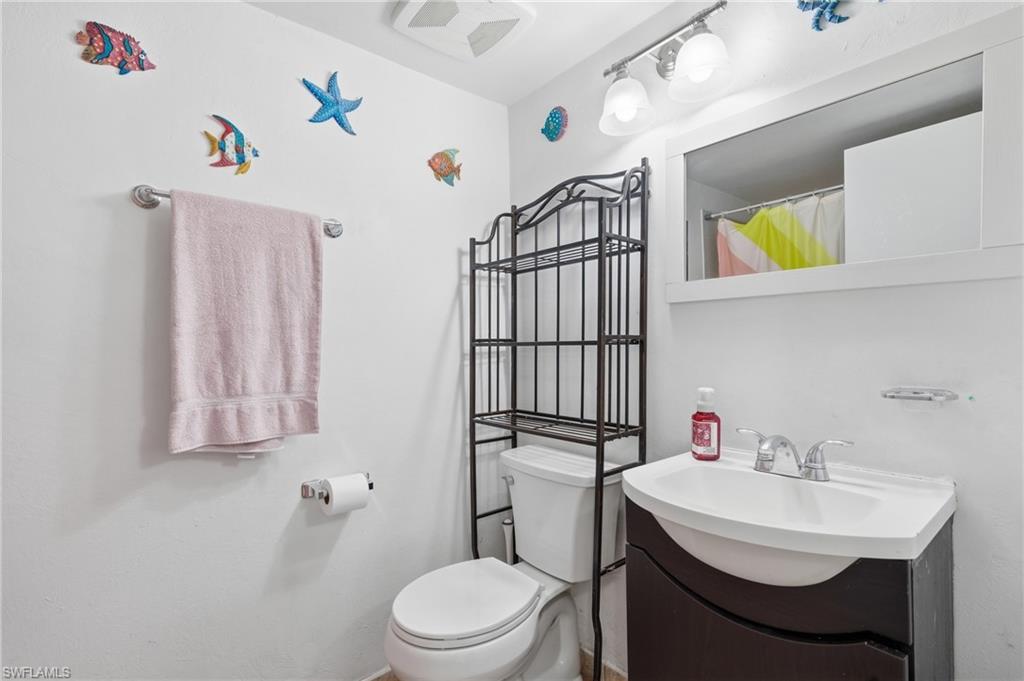 Bathroom featuring a white vanity with an integrated sink, a chrome-finish faucet, and a wall-mounted mirror