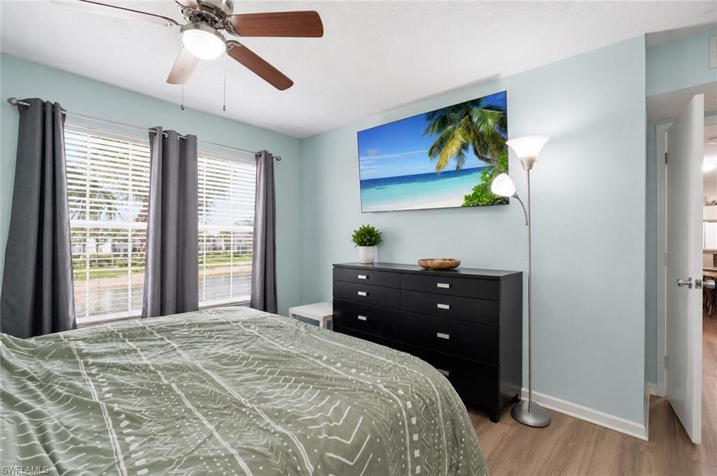 Wood-finish flooring, two large windows with blinds, and a ceiling fan with integrated lighting