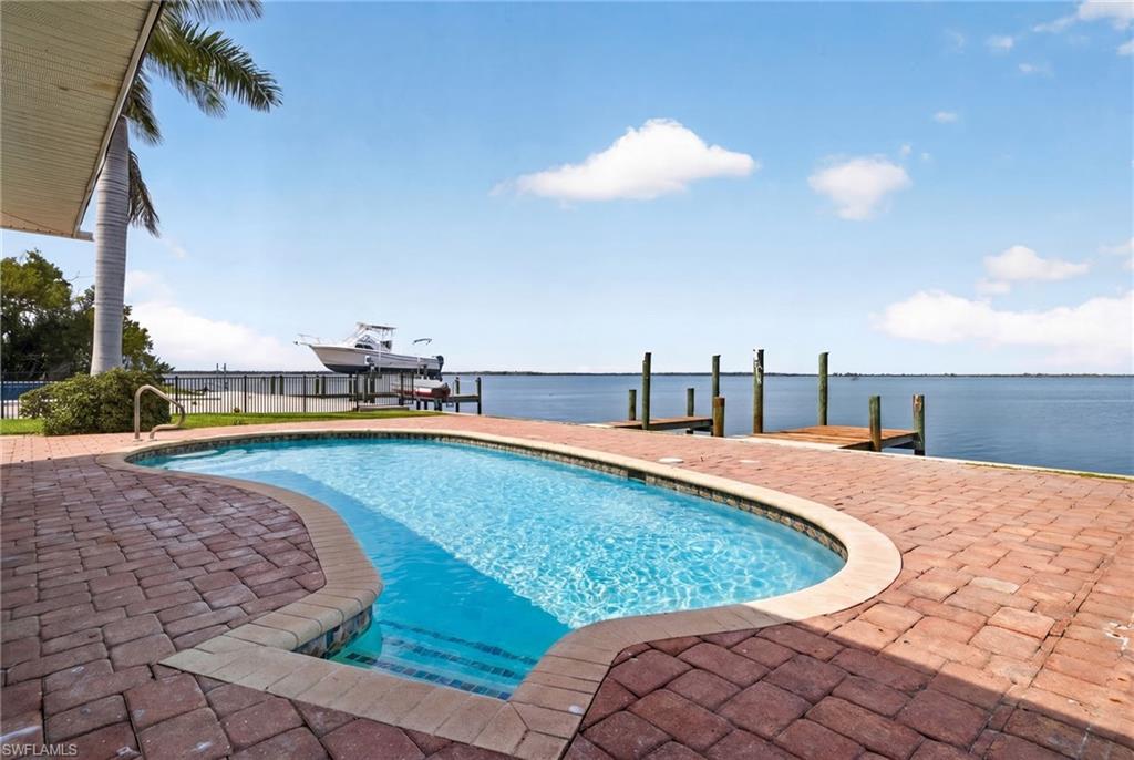 Freeform swimming pool with integrated steps, surrounded by brick paver decking