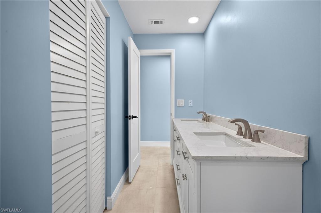 Dual vanity with white cabinetry and integrated sinks, brushed nickel faucets, and a light-toned countertop