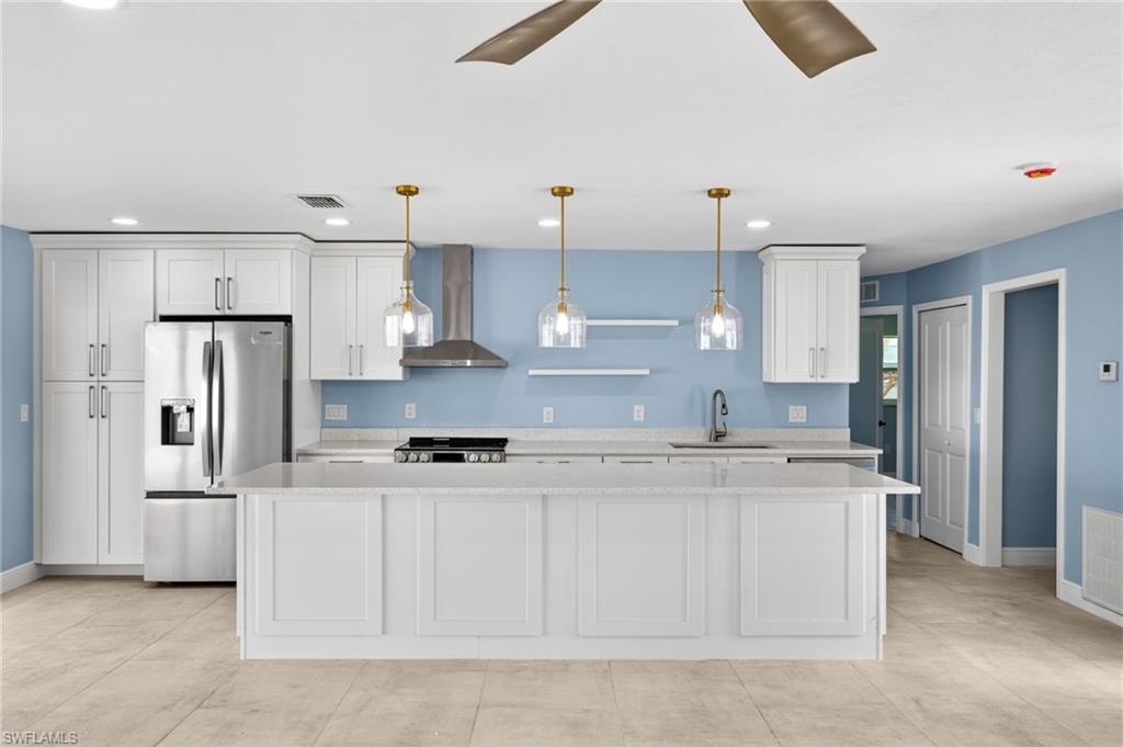 Kitchen featuring white shaker cabinetry, stainless steel appliances, a center island with countertop seating, and light-toned tile flooring