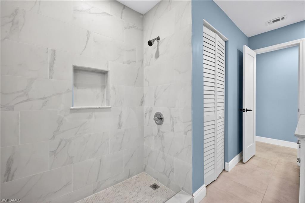 Spacious shower with large format, marble-look wall tiles and a built-in shower niche