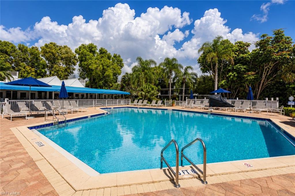 Community swimming pool featuring a brick paver deck and lounge seating